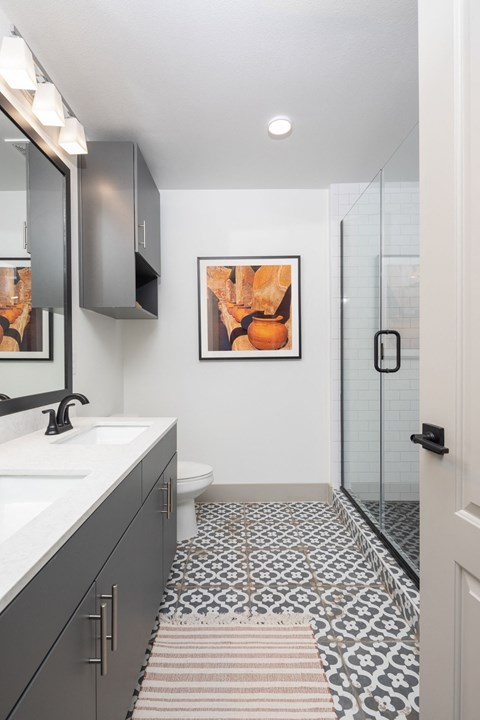 A bathroom with a toilet, sink, and a patterned tile floor.