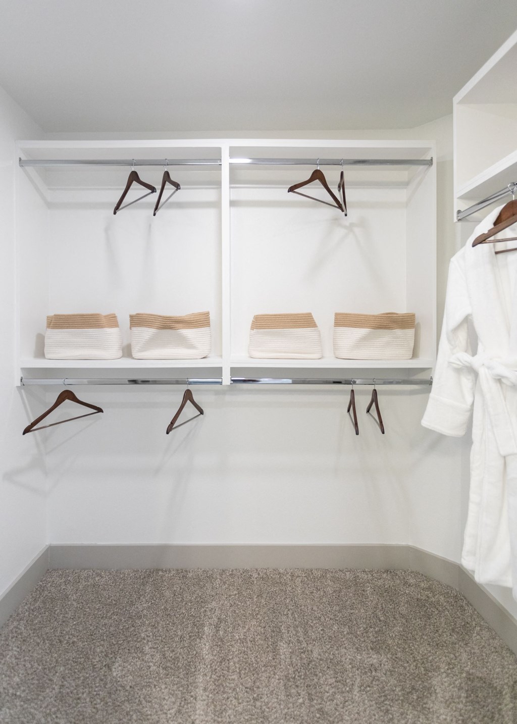 a walk in closet with white walls and shelves with white towels and hangers