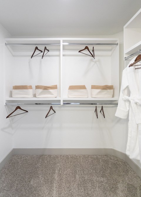 A white closet with two shelves and two hangers.
