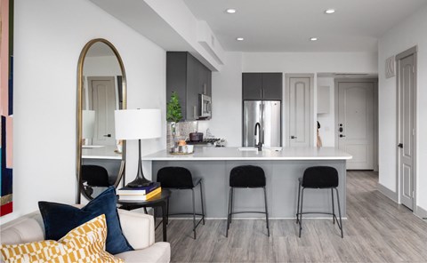 A modern kitchen with a white countertop and black bar stools.
