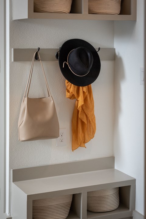 A black hat and a mustard yellow scarf are hanging on a hook.