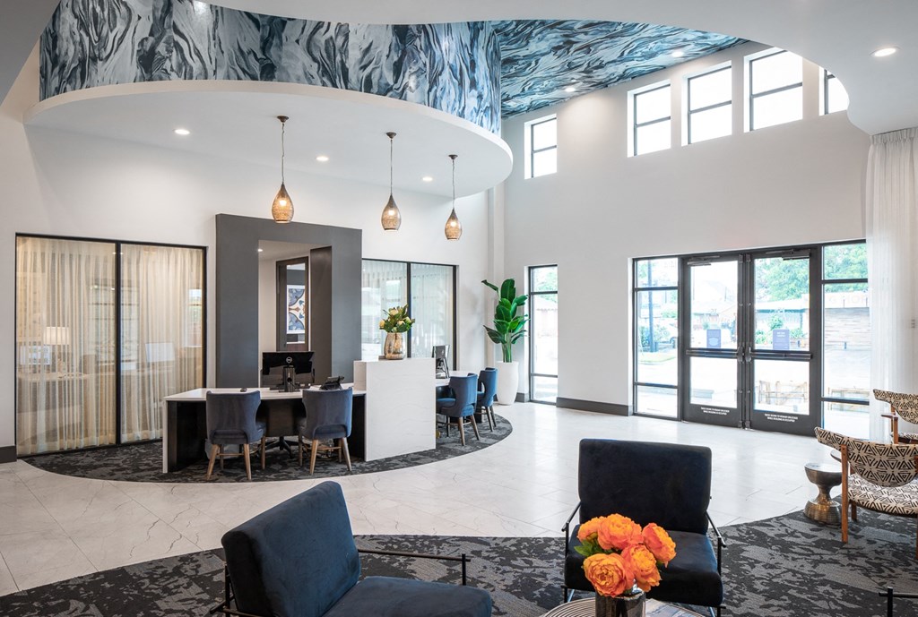 the lobby of a building with blue chairs and a table and a large circular ceiling