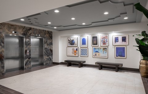 the lobby of a building with paintings on the wall and two elevators
