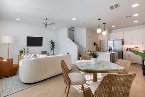 A modern living room with a white sofa, a TV, and a dining table with chairs.