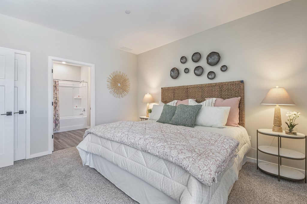 A bedroom with a large bed and a nightstand with a lamp.