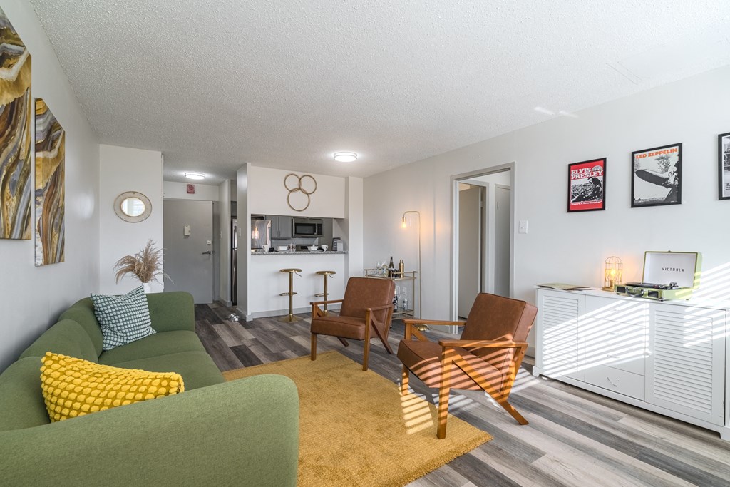 a living room with a green couch and chairs and a kitchen with a dining area