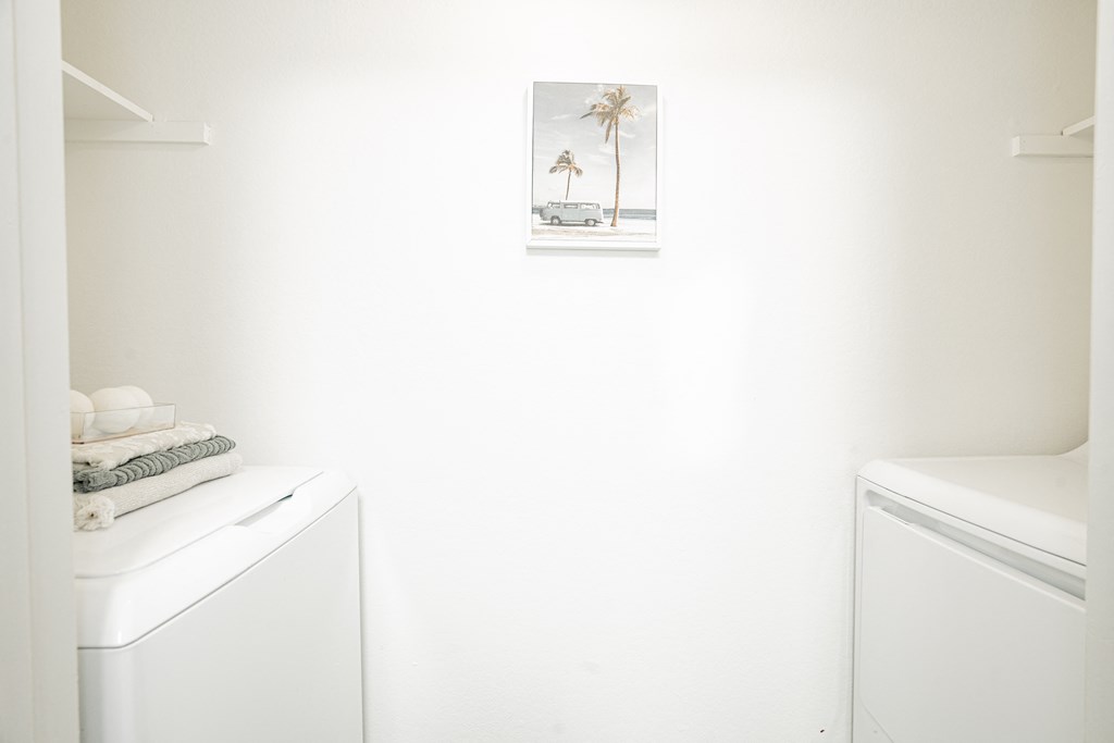 a small bathroom with a washer and dryer and a picture of a beach