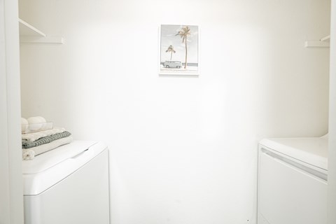 a small bathroom with a washer and dryer and a picture of a beach