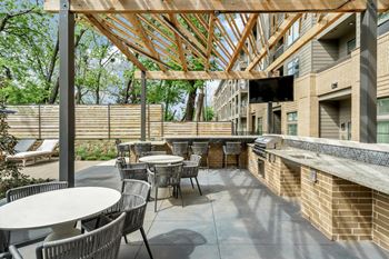 A patio with tables and chairs under a wooden roof.