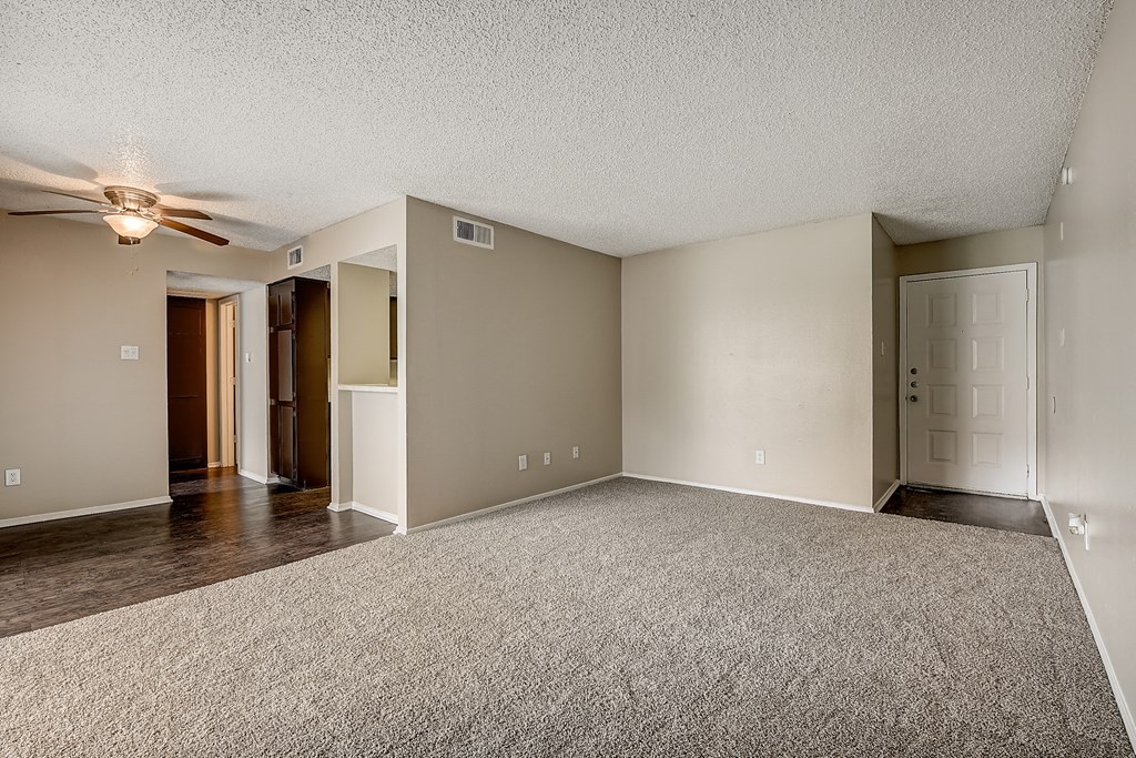 an empty living room with a ceiling fan