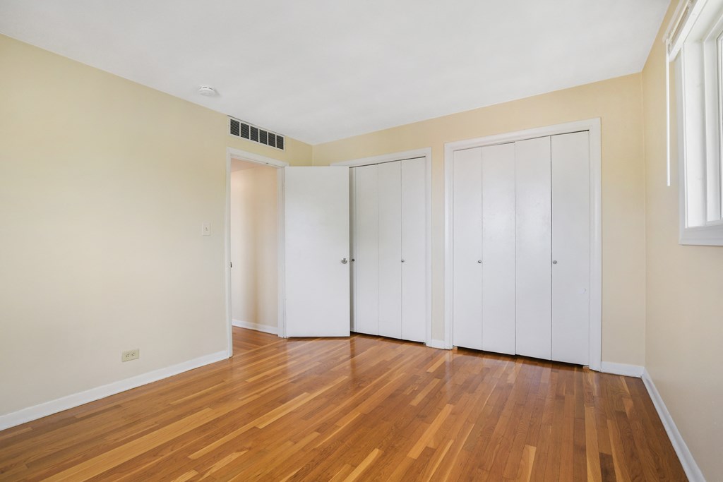 an empty room with wood floors and white closets