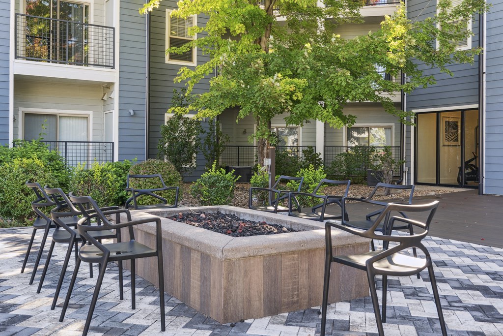 A patio with chairs and a fire pit in front of a building.