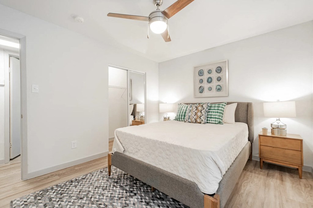 A bedroom with a bed, nightstand, and a ceiling fan.
