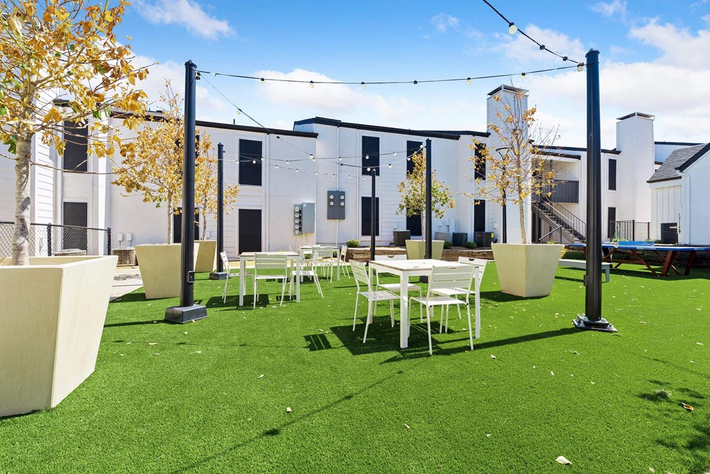 a courtyard with tables and chairs and a building in the background