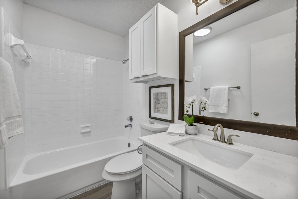 A white bathroom with a toilet, sink, and bathtub.