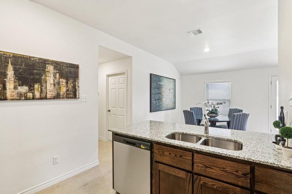 A kitchen with a large painting on the wall and a dishwasher in the middle.