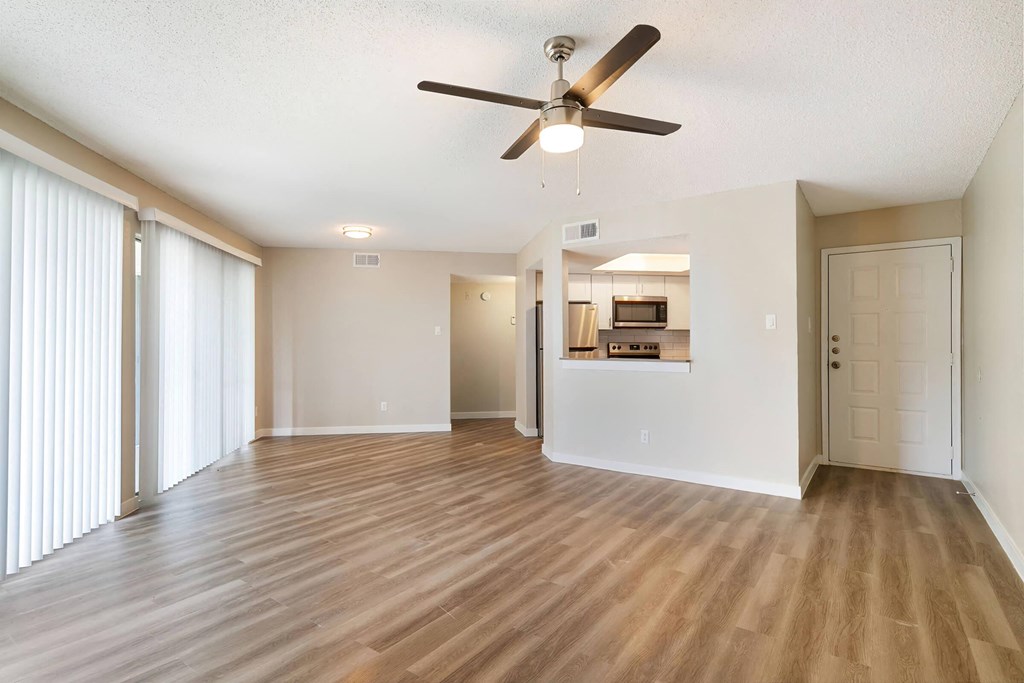 an empty living room with a ceiling fan
