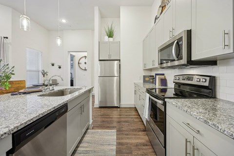 A kitchen with a stainless steel refrigerator and a microwave above the stove.