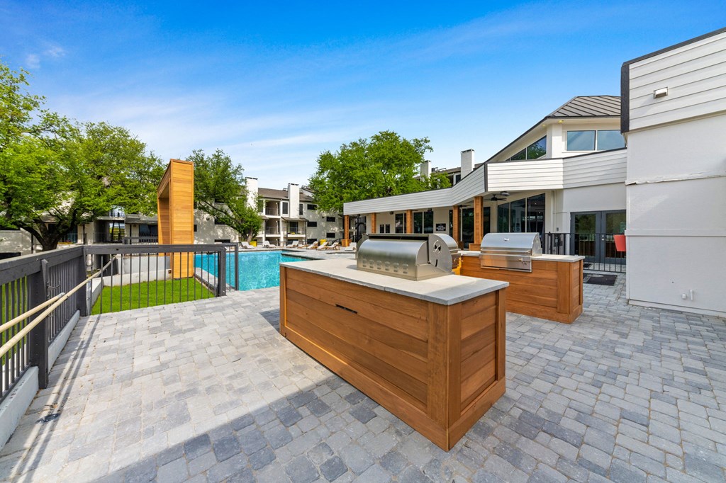 a backyard patio with a grill and a swimming pool