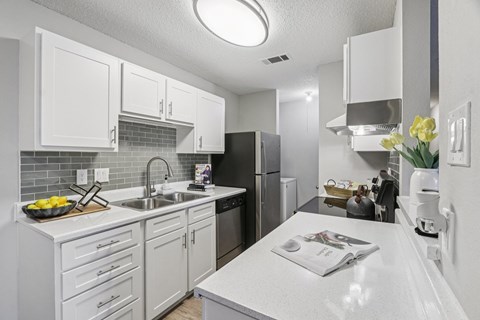 A kitchen with white cabinets and a white countertop.