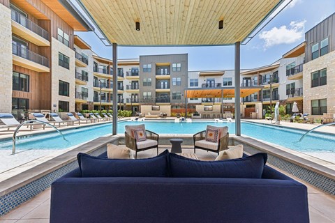 A large blue couch is in the foreground of a pool area with a wooden ceiling.