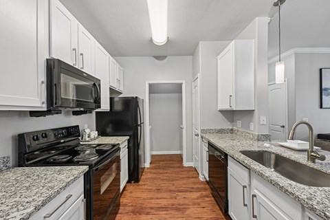 A kitchen with black appliances and white cabinets.