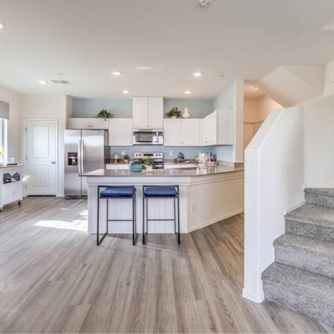 A kitchen with white cabinets and a blue bar stool.