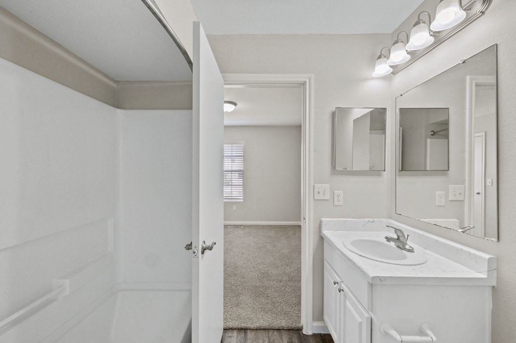 A white bathroom with a sink, mirror, and lighting.
