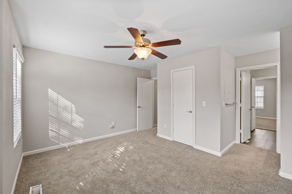 A room with a ceiling fan and carpeted floor.
