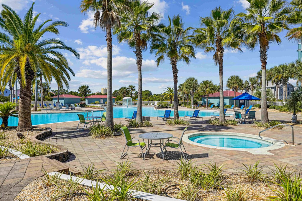 A pool surrounded by palm trees and a table with chairs.