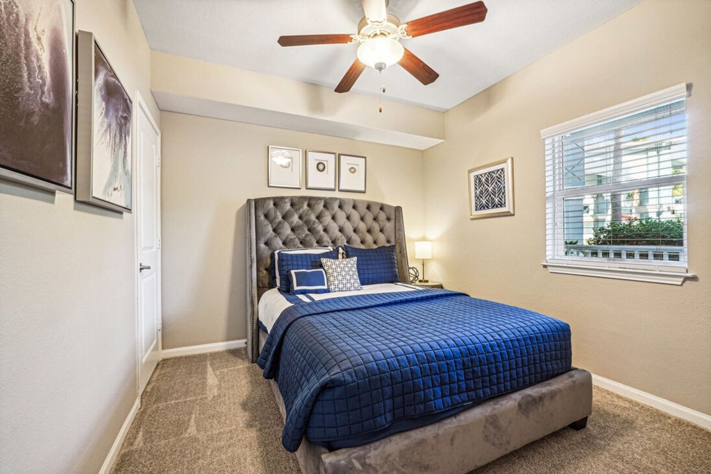 A bedroom with a bed, a ceiling fan, and a window.