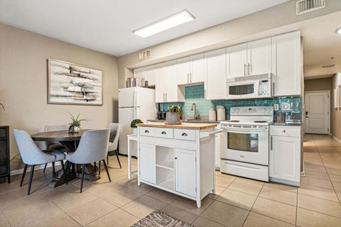 A kitchen with white appliances and a dining table with chairs.