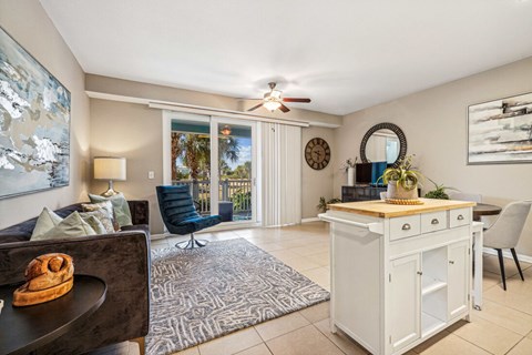 A living room with a couch, chair, and a table with a clock on the wall.