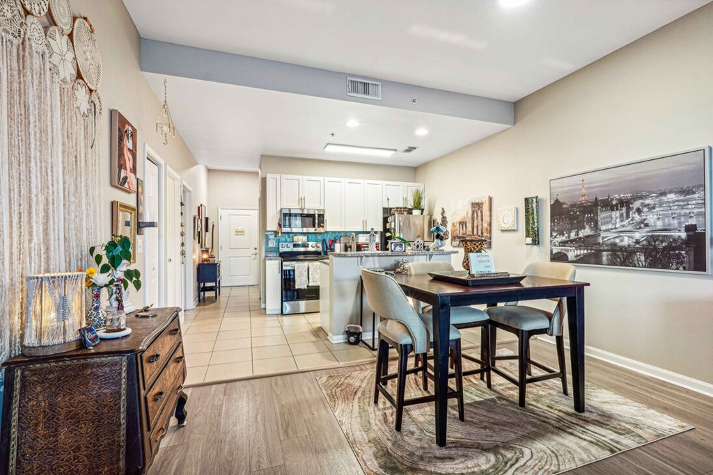 A kitchen with a dining table and chairs in the foreground.