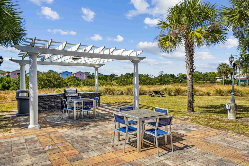 A patio with a table and chairs under a white pergola.