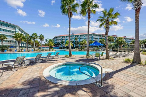 A pool surrounded by palm trees and lounge chairs.