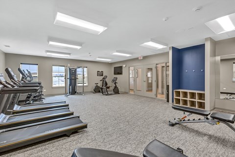 A spacious gym with treadmills, elliptical machines, and a weight room.