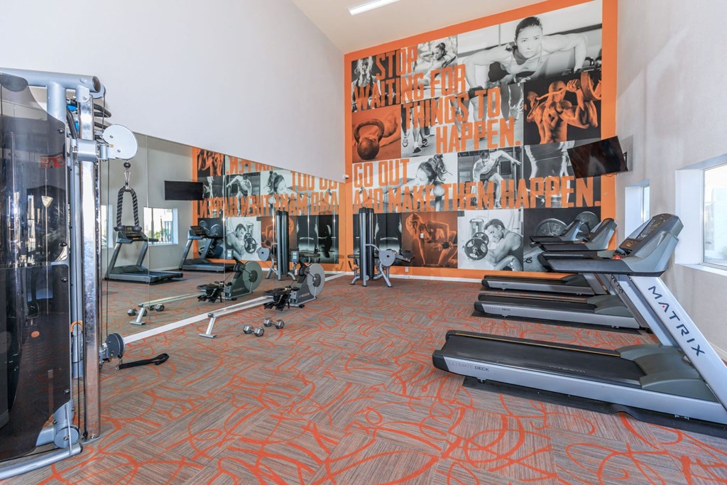 a gym with cardio equipment and a large mural on the wall