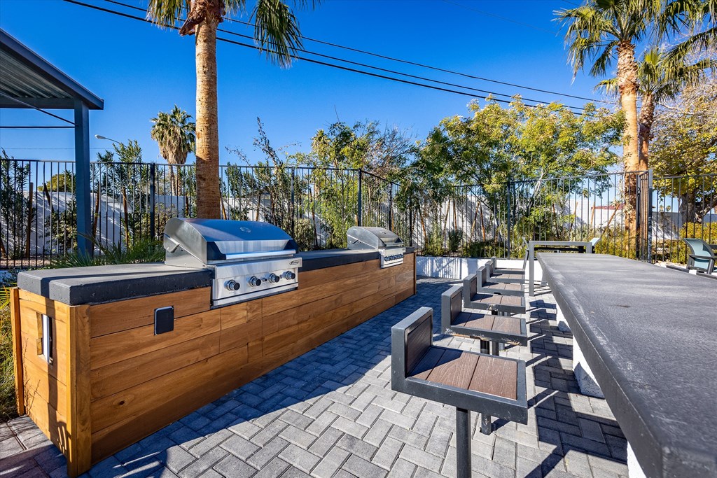 a patio with a grill and tables and chairs