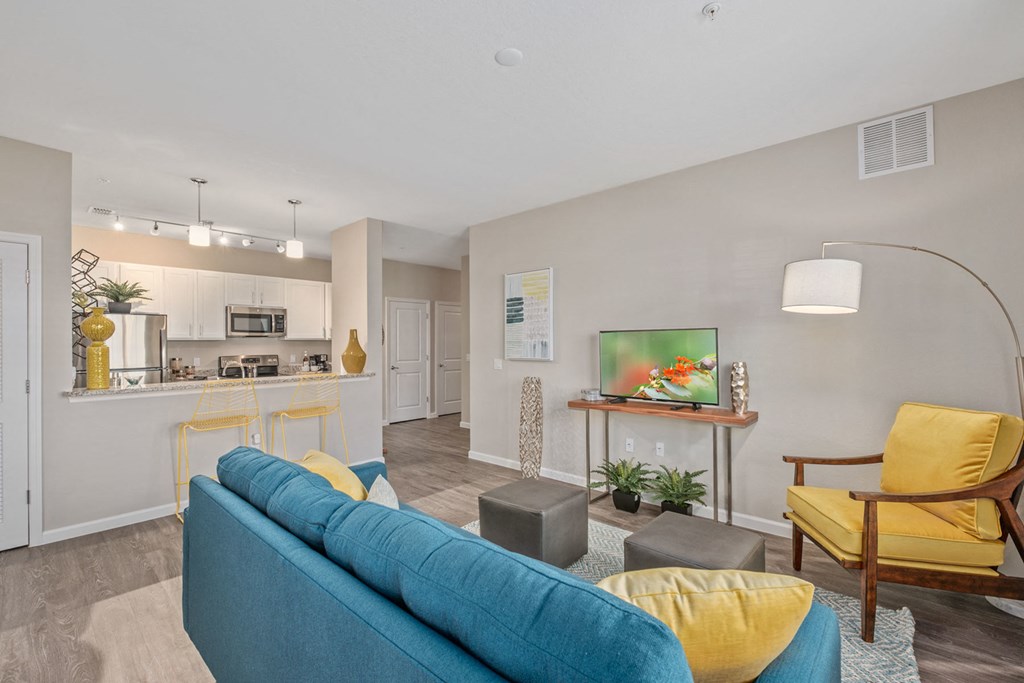 a living room and kitchen with a blue couch and yellow chairs