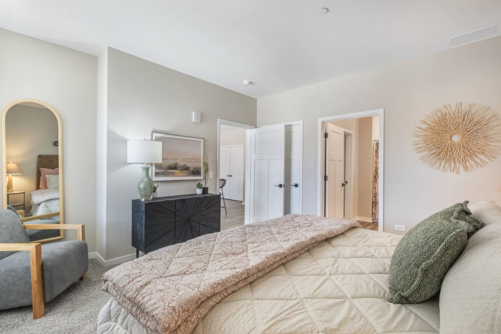 A bedroom with a large bed and a chair.