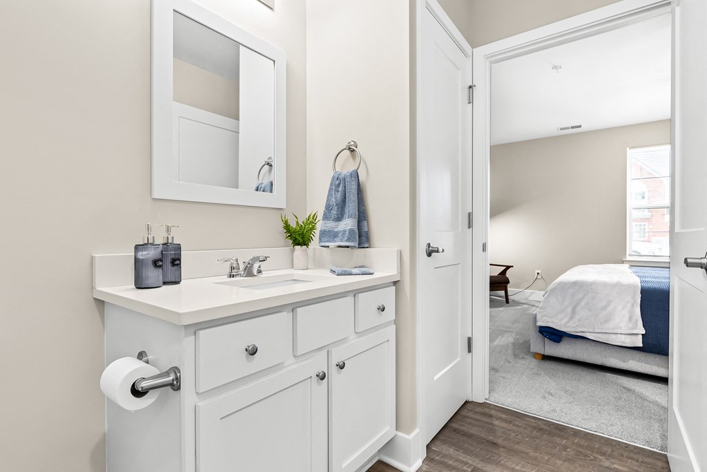 a bathroom with a sink and a mirror and a door to a bedroom