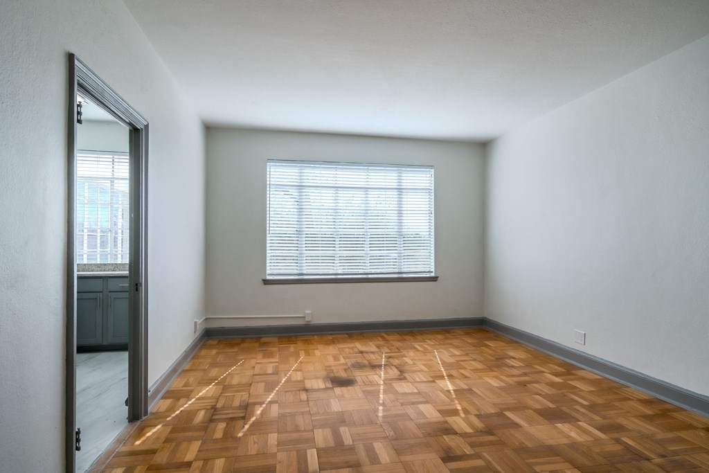 an empty living room with wood flooring and a window