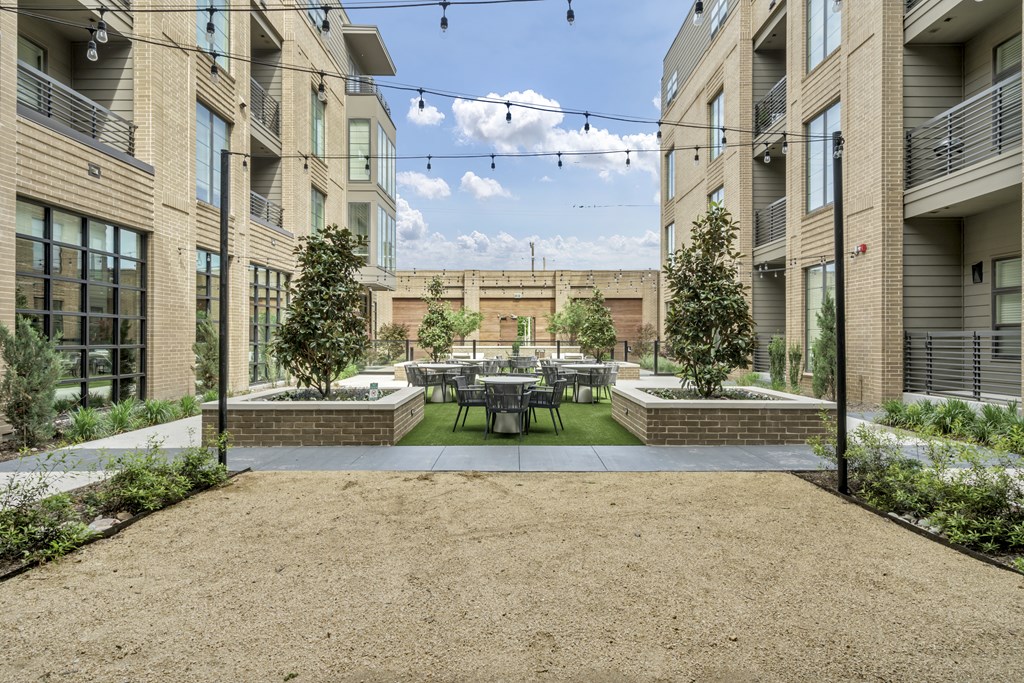 A courtyard surrounded by buildings with a table and chairs in the middle.