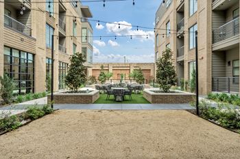 A courtyard surrounded by buildings with a table and chairs in the middle.