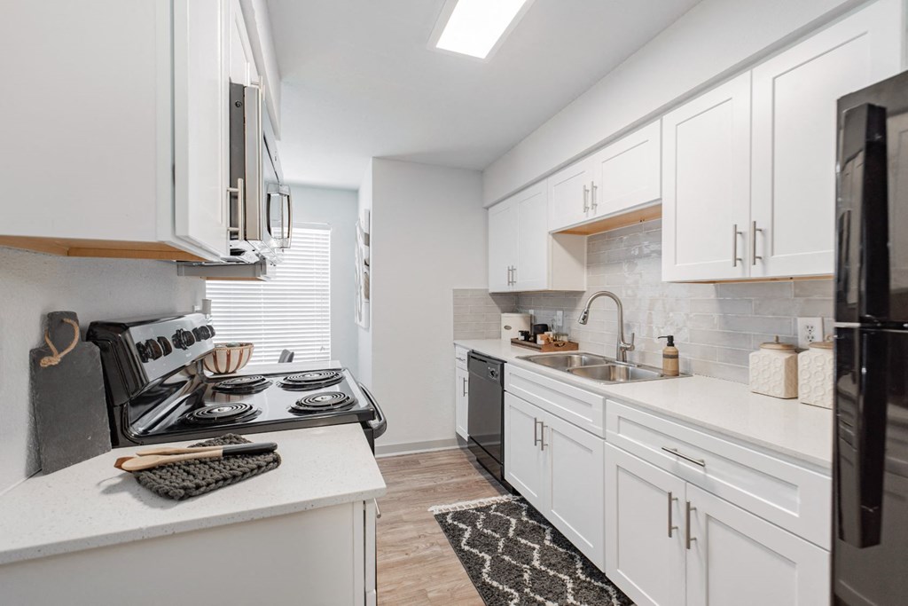 A kitchen with white cabinets and black appliances.
