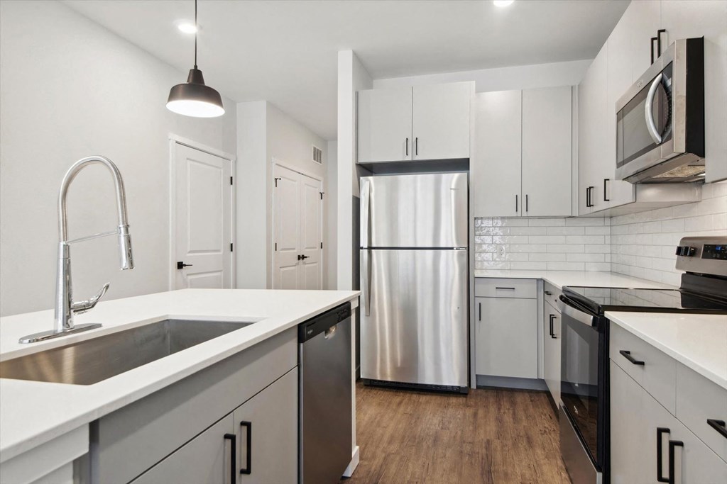 a kitchen with white cabinets and a stainless steel refrigerator