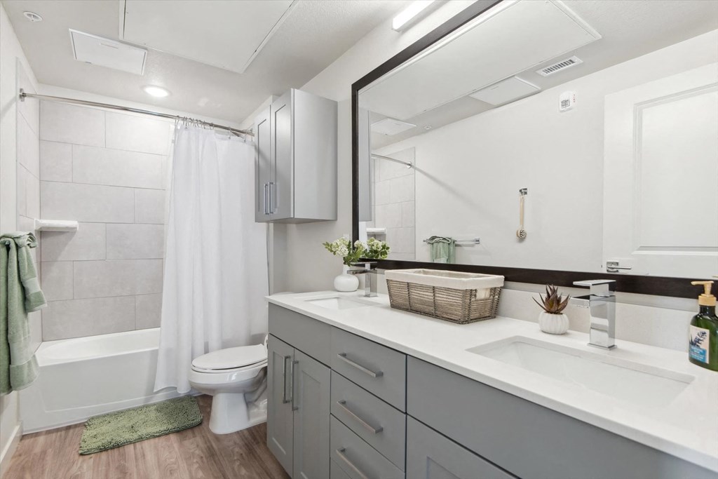 A bathroom with a white toilet, a white sink, and a white bathtub with a white shower curtain.