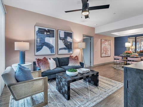 A modern living room with a black and white coffee table, a grey sofa, a blue chair, and a painting on the wall.