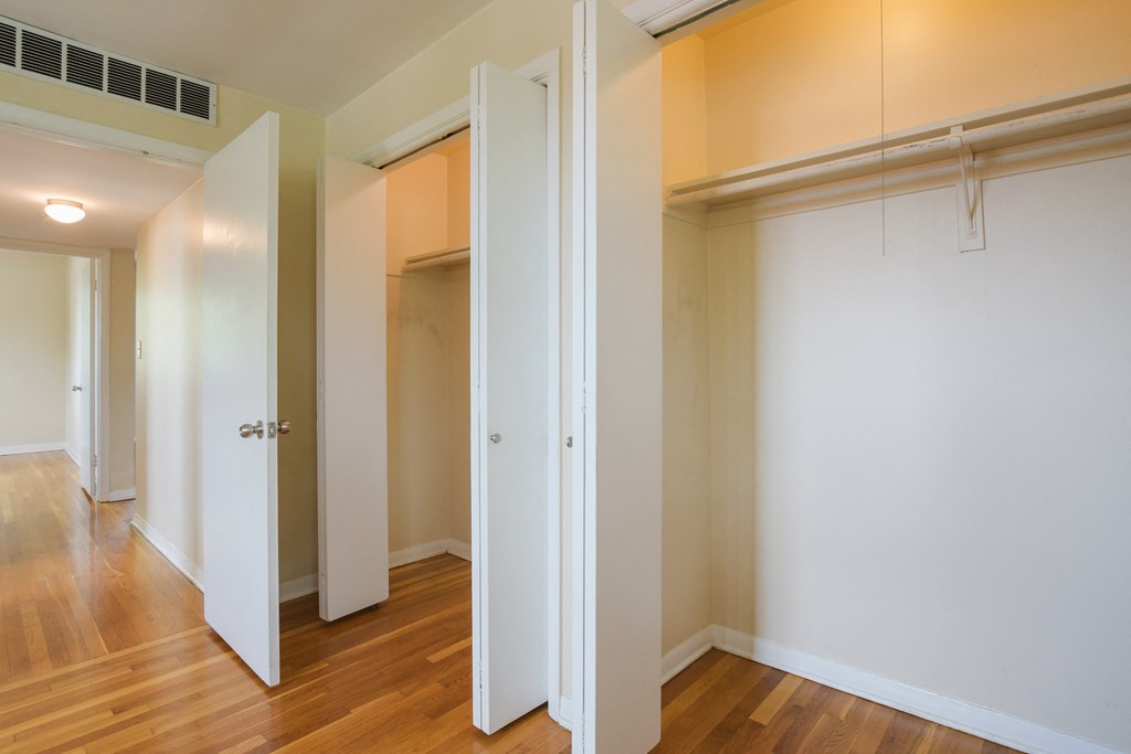 a bedroom with two closets and a wood floor and white doors